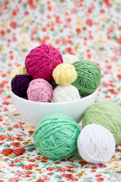 A lot of bright balls of knitting on the background of a red flower — Stock Photo, Image