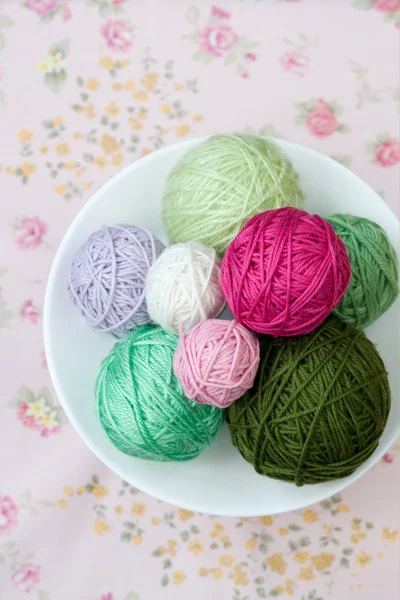 Viele helle Strickkugeln auf dem Hintergrund einer rosa Blume — Stockfoto