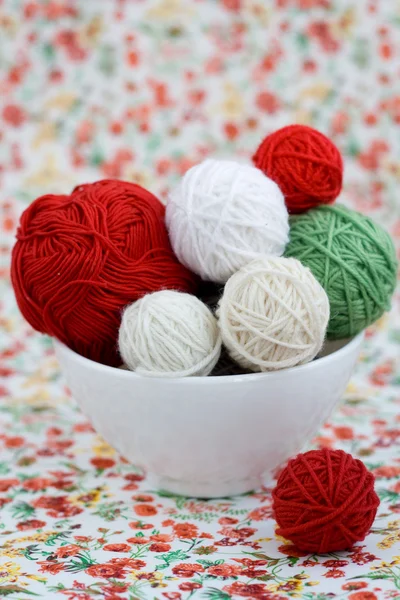 A lot of bright balls of knitting on the background of a red flower — Stock Photo, Image