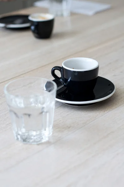 Una tazza di caffè nero e un bicchiere d'acqua sul tavolo — Foto Stock