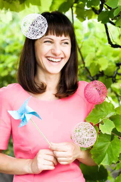 Schönes Mädchen lacht und hält eine Windmühle — Stockfoto