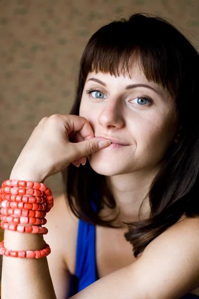 Portret van een mooie jonge brunette met rode kralen — Stockfoto