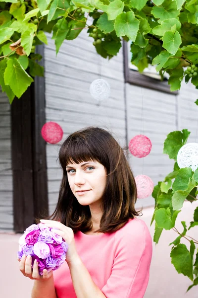 La fille dans une robe rose tenant un bouquet de fleurs violettes — Photo