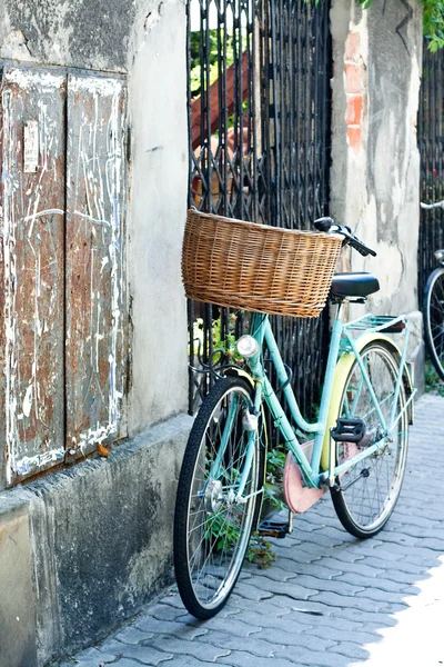 Bicicleta vieja con cesta de mimbre de pie en la calle de la ciudad — Foto de Stock