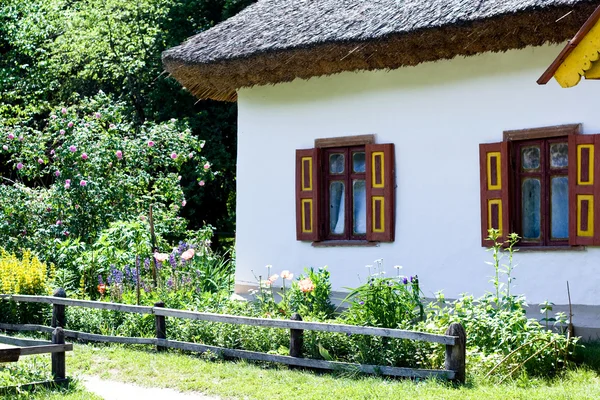 Una vieja cabaña rural ucraniana y un parterre —  Fotos de Stock