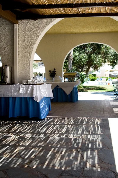 Una mesa con un mantel azul, pared amarilla y patrón de sombras en el suelo — Foto de Stock