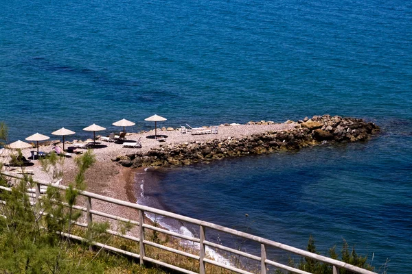 Il mare azzurro, la spiaggia e gli ombrelloni in spiaggia — Foto Stock