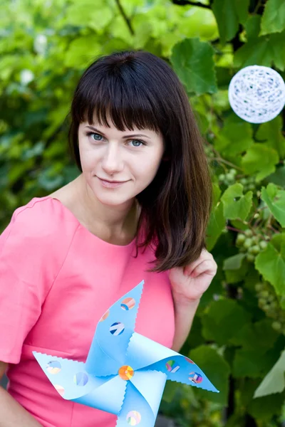 Schönes Mädchen lacht und hält eine Windmühle — Stockfoto