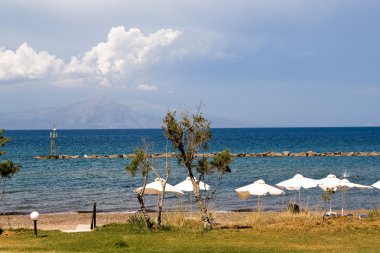 ağaç, mavi deniz, dağlar ve beyaz bulutlar