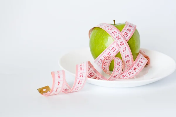 Manzana verde y cinta métrica en un plato blanco —  Fotos de Stock