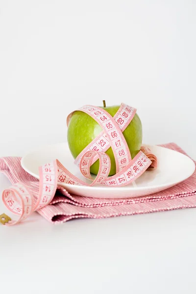 Groene appel en meetband op een witte plaat — Stockfoto