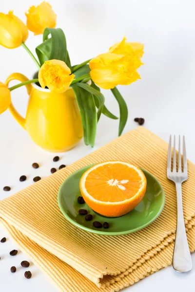 Yellow jug with yellow tulips and juicy oranges for breakfast — Stok fotoğraf