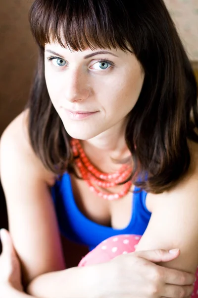 Portret van een mooie jonge brunette met rode kralen — Stockfoto