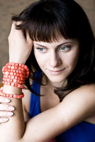Portrait of a beautiful young brunette with red beads — Stock Photo, Image