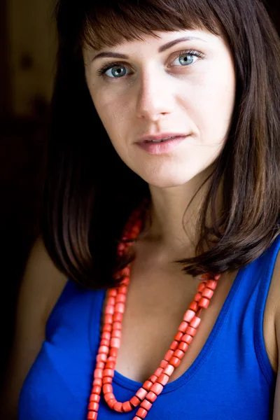 Portrait of a beautiful young brunette with red beads — Stock Photo, Image