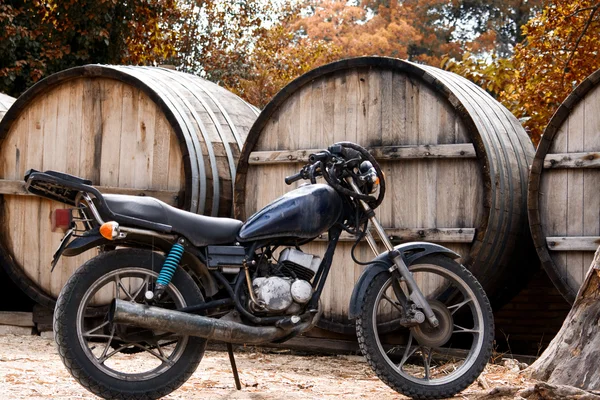 Moto noire sur fond avec un grand tonneau pour le vin — Photo