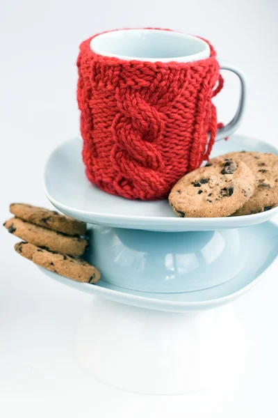 Blå kopp med röd stickad pärm och kakor med choklad — Stockfoto