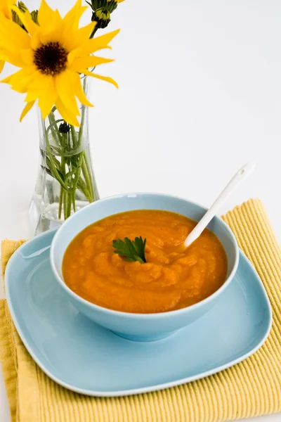 Zuppa di zucca in un piatto blu e un mazzo di fiori gialli — Foto Stock