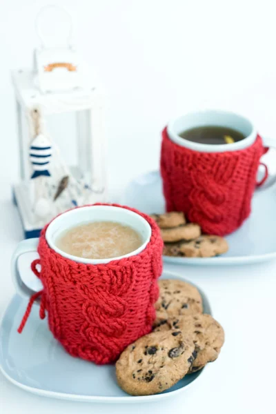 Dvě modré šálky v pletených kryty a čokoládové cookies — Stock fotografie