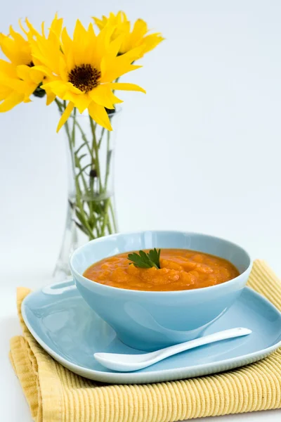 Zuppa di zucca in un piatto blu e un mazzo di fiori gialli — Foto Stock
