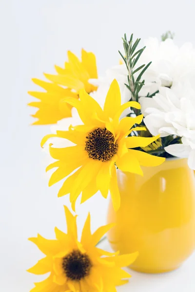 Żółty dzbanek z żółtych i białych kwiatów na jasnym tle — Zdjęcie stockowe
