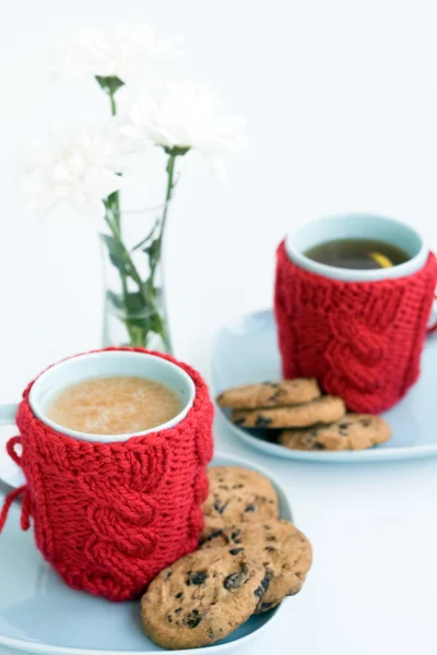 Twee blauwe kopjes in gebreide covers en chocolade koekjes — Stockfoto