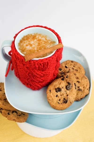 Blaue Tasse mit rotem Stricküberzug und Kekse mit Schokolade — Stockfoto