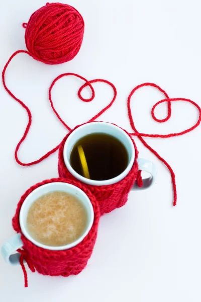 Dois copos azuis em coberturas tricotadas e dois corações de fios — Fotografia de Stock
