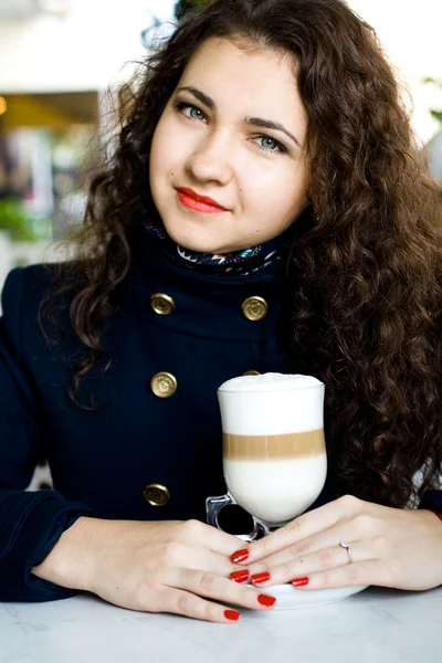 Young beautiful brunette with a delicious latte in a street cafe — Stock Photo, Image