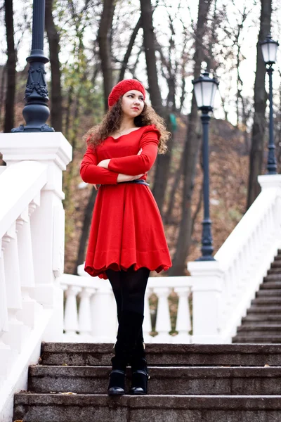 Junge schöne Brünette in einem roten Kleid steht auf der Treppe — Stockfoto
