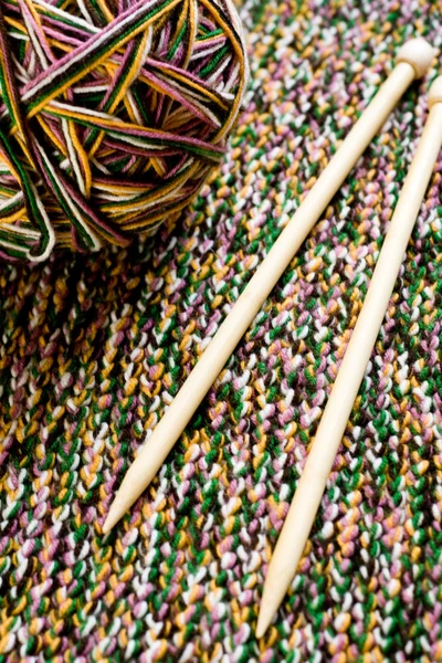 Great ball of colored yarn, wooden knitting needles and knit fabric — Stock Photo, Image