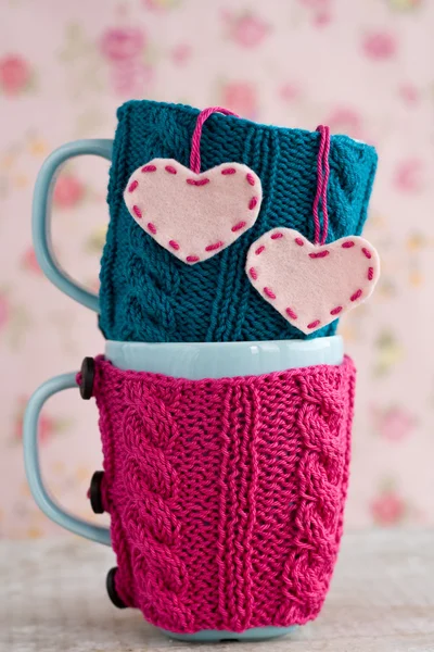 Två blå koppar i blå och rosa tröja med filt hjärtan — Stockfoto