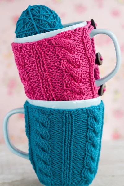 Two blue cups in blue and pink sweater with ball of yarn for knitting — Stock Photo, Image