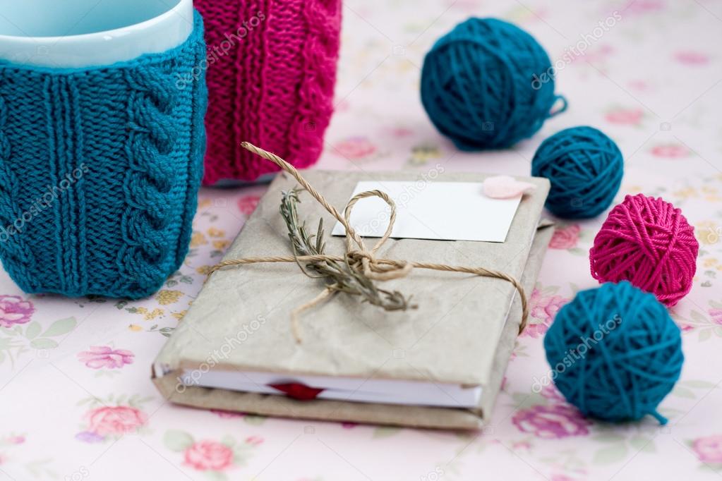 Two blue cups in blue and pink sweater with ball of yarn for knitting