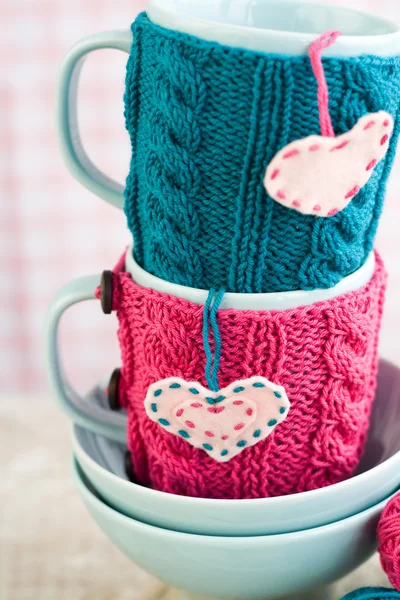 Two blue cups in blue and pink sweater with felt hearts — Stock Photo, Image