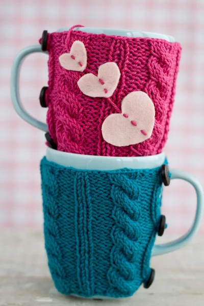 Two blue cups in blue and pink sweater with felt hearts — Stock Photo, Image