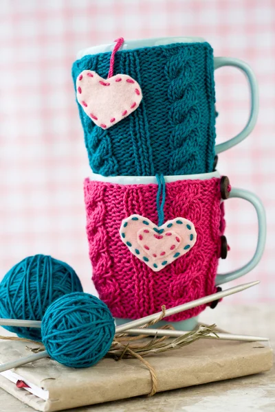Dwa niebieskie filiżanki w niebieski i różowy sweterek z filcu serca — Zdjęcie stockowe