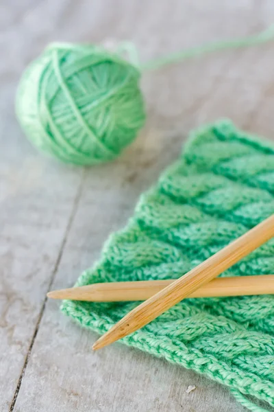 Strickmuster und Nadeln auf einem hölzernen Hintergrund — Stockfoto