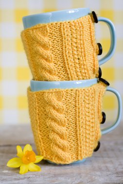 kumaş üzerinde sarı kazaklı iki mavi kupa