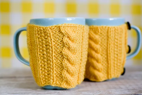 Dos tazas azules en suéter amarillo sobre una tela — Foto de Stock