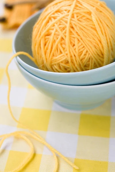 Yellow ball of yarn for knitting in blue plate and pattern — Stock Photo, Image