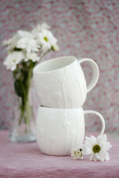 Två vita koppar och en bukett med vita blommor — Stockfoto