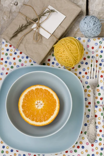 Сочный апельсин на голубой тарелке - это старая подушечка и нитки пряжи — стоковое фото