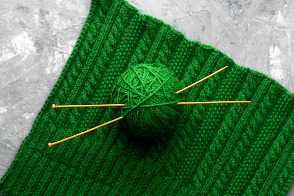 緑のニットのテクスチャの背景に2つの編み針と糸の緑のボール — ストック写真