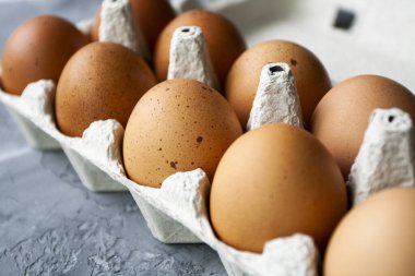 Benekli kahverengi yumurtalar gri beton bir masada kağıt bir torbanın içinde yatıyor.