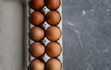 Benekli kahverengi yumurtalar gri beton bir masada kağıt bir torbanın içinde yatıyor.