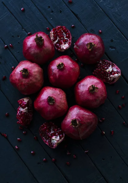 Lots Juicy Red Pomegranates Lie Black Wooden Background — Stock Photo, Image