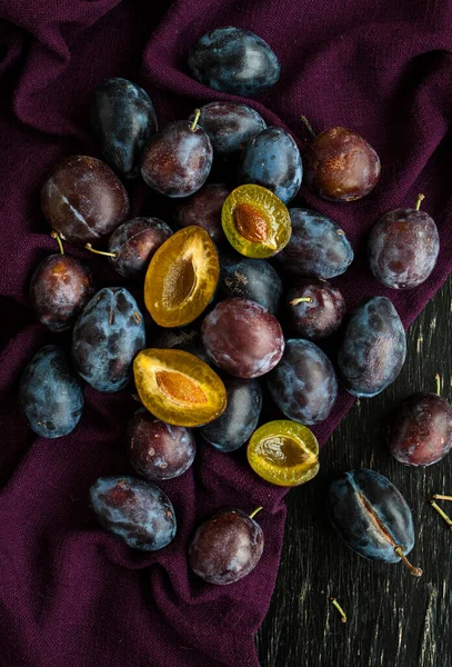 Dark Ripe Juicy Plums Lie Purple Tablecloth Which Lie Black — Stok fotoğraf