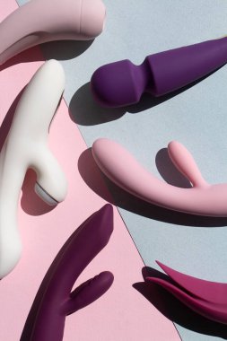 Mavi ve pembe arka planda farklı seks oyuncakları koleksiyonu. Yetişkinler için seks oyuncakları, vibratörler, klitoral uyarıcılar.