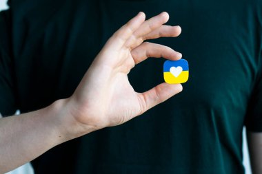 Rusya ile savaşta Ukrayna 'ya destek. Genç bir adam Ukrayna 'nın stilize edilmiş bayrağını kalbinin yanında tutuyor. Kavramsal fotoğraf.